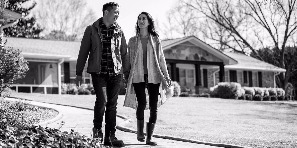 Alt Text	A man and woman in nice but casual fall clothes smile and chat as they walk down a paved pathway through the front yard of a well-maintained ranch house with a brick and stone façade.