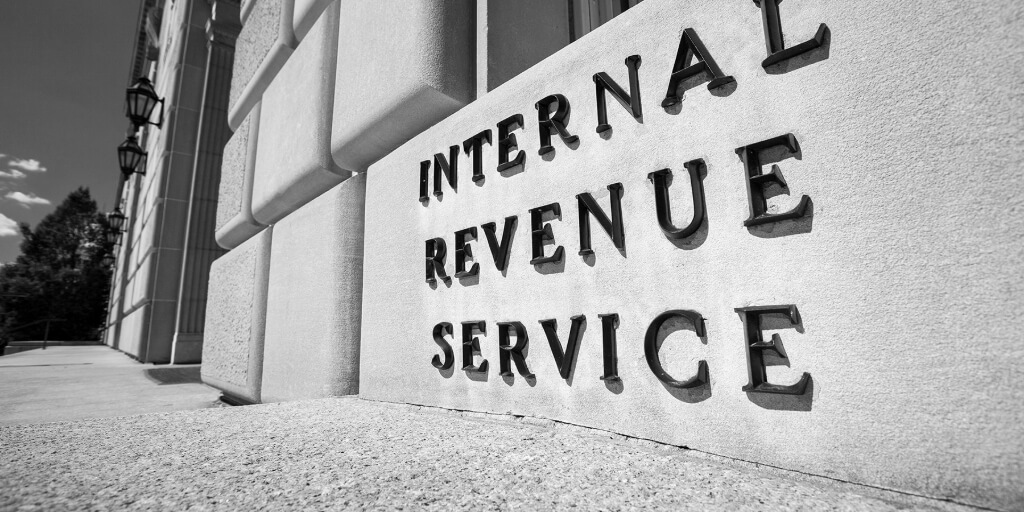 A large sand-colored building bears the words “INTERNAL REVENUE SERVICE” in large capital letters.